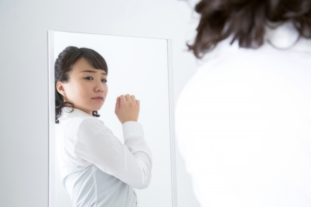 猫背が気になり鏡で姿勢を確認する女性